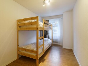 Une chambre avec un lit superposé, une fenêtre et un radiateur.