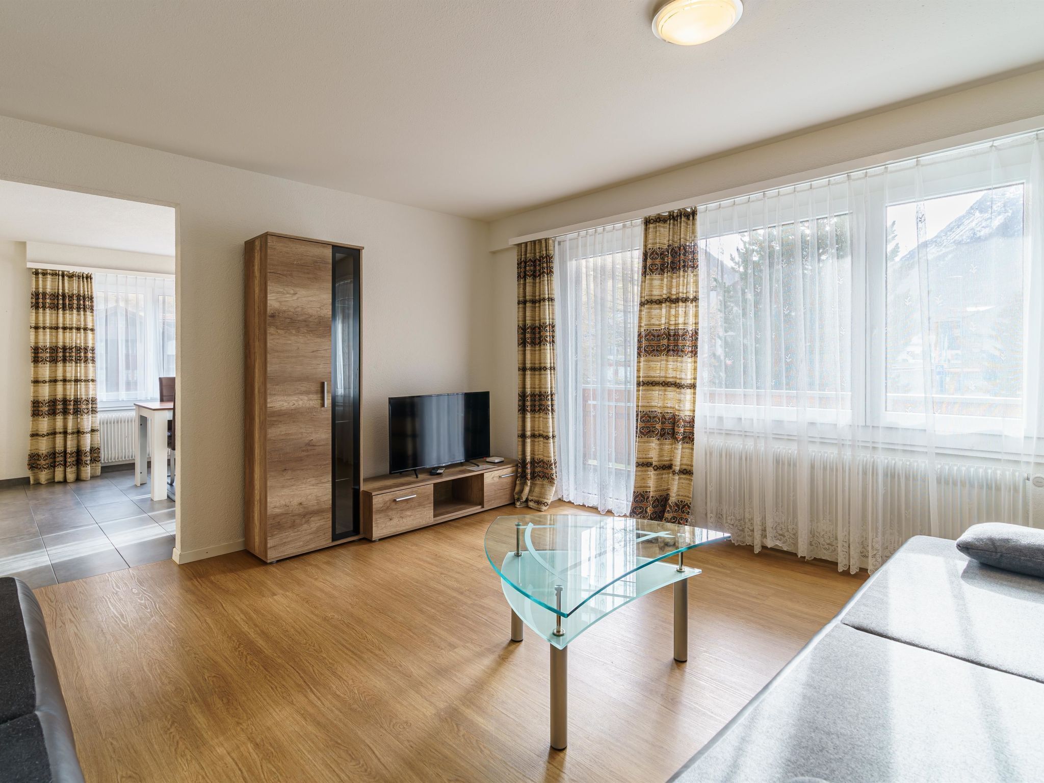 A modern living room with a glass coffee table, a TV, and a sofa.