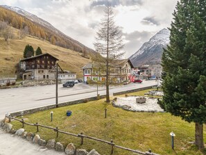 A mountain village with traditional wooden buildings, a paved road, and a parking area. - Haus City by Interhome (Saas-Grund)