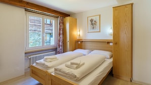 A room with a bed, a window, a radiator, and a wooden door. - Haus Alfa by Interhome (Saas-Fee)