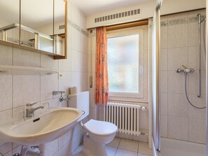 Ein Badezimmer mit Waschbecken, Toilette, Dusche und einem Fenster mit Vorhang.