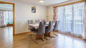 Ein Essbereich mit einem Tisch für vier Personen, Stühlen, einem Gemälde an der Wand und einem Fenster mit Vorhängen.