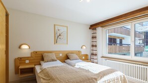 Une chambre à coucher avec un lit, des tables de chevet, une fenêtre donnant sur un paysage agréable et un tableau accroché au mur.
