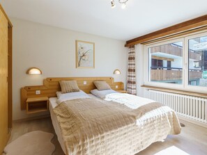 Ein Schlafzimmer mit Bett, Nachttischen, einem Fenster mit Aussicht und einem Wandbild.