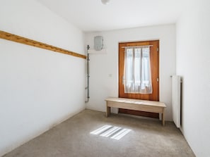 A narrow hallway with a wooden bench, a radiator, and a door with a curtain. - Haus Slalom by Interhome (Saas-Fee)