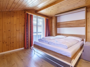 A wooden-paneled bedroom with a bed, curtains, and a window. - Haus Slalom by Interhome (Saas-Fee)