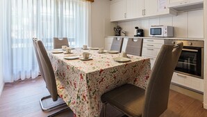 A dining area with a table set for four, a microwave, and a stove in the background. - Haus Slalom by Interhome (Saas-Fee)