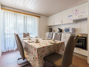A dining area with a table set for four, a microwave, and a stove in the background. - Haus Slalom by Interhome (Saas-Fee)