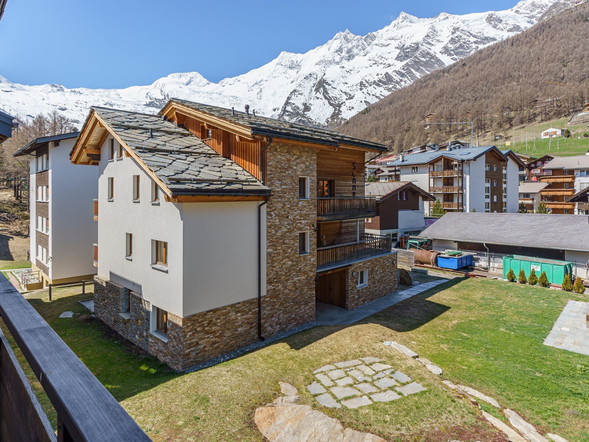 A multi-story building with a stone facade and wooden accents, set against a backdrop of snow-capped mountains.