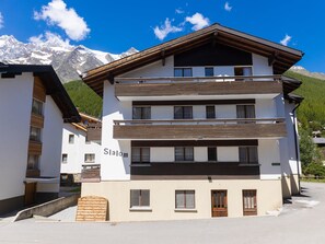 Ein mehrstöckiges Hotel mit modernem Design, das Balkone und einen Blick auf schneebedeckte Berge bietet.