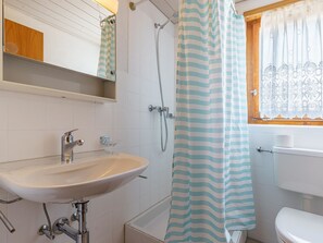 Ein Badezimmer mit weißem Waschbecken, einer Dusche und einer Toilette.