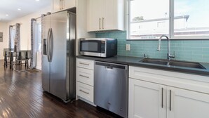 A modern kitchen with stainless steel appliances, white cabinetry, and a window overlooking a residential area. - Cozy getaway (Oakland)