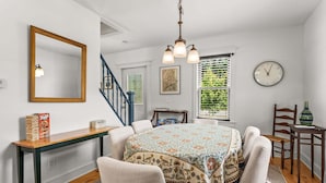 A dining area with a table set for four, a wooden console table with books, a mirror, and a clock on the wall. - Cross Road Cottage - NEW! Home in Hancock (Hancock)