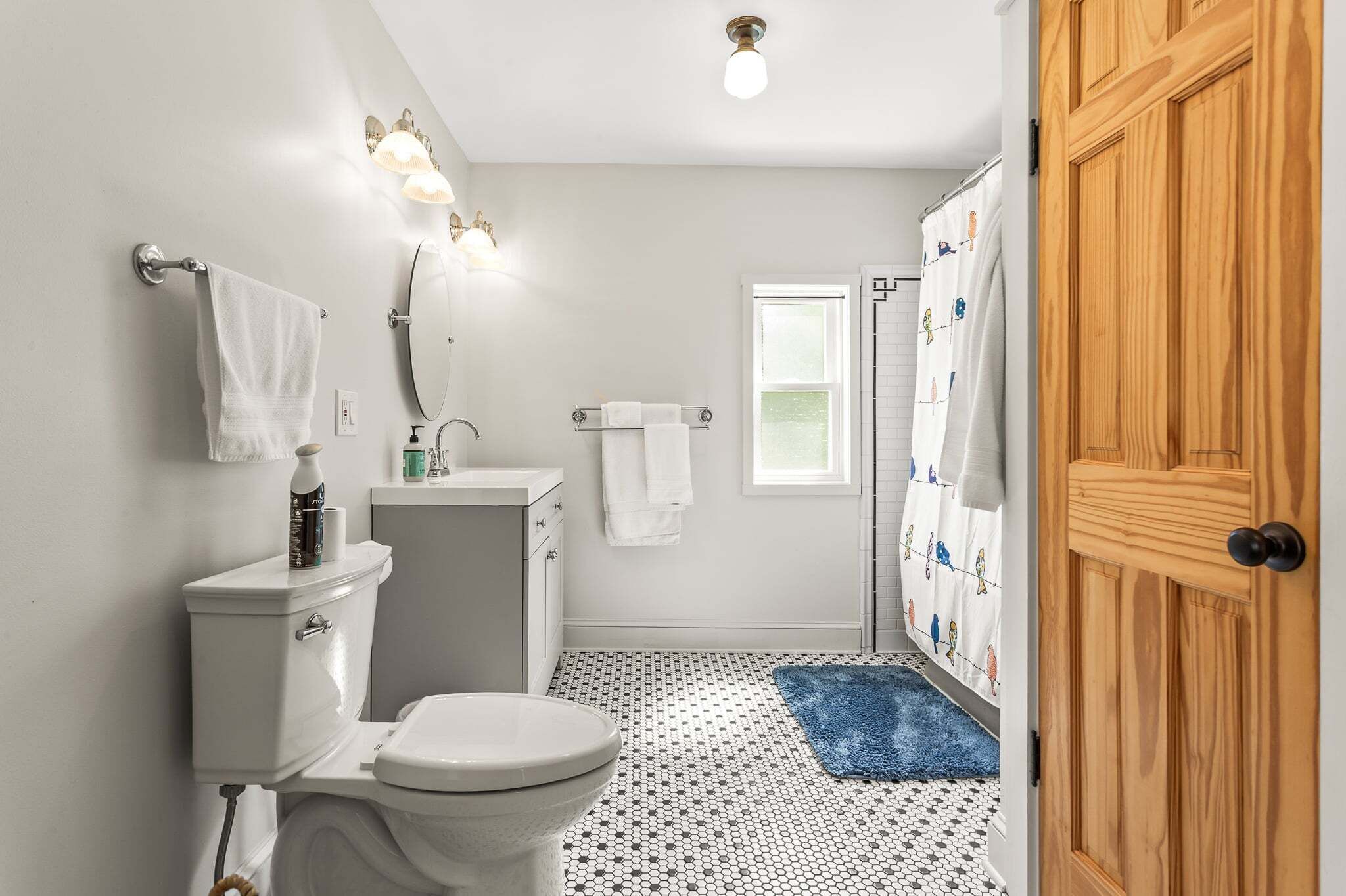 Ein Badezimmer mit Toilette, Waschbecken, Spiegel und Duschvorhang.