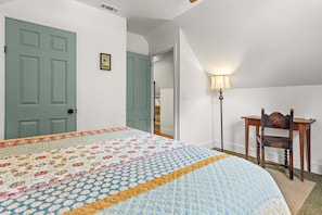 Ein Schlafzimmer mit Bett, Stuhl, Lampe und Tür.