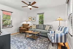 Ein Wohnzimmer mit einer Couch, Sesseln, einem Couchtisch und einem Deckenventilator.