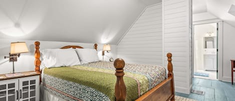 A bedroom with a wooden four-poster bed, a nightstand with a lamp, a wardrobe, and a ceiling fan.