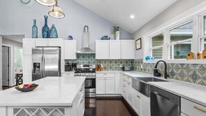 A modern kitchen with white cabinetry, stainless steel appliances, and a marble countertop. - Patten Pond Retreat - NEW! Waterfront (Surry)