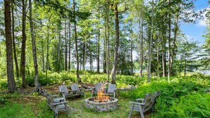 A forest with a fire pit and chairs. - Patten Pond Retreat - NEW! Waterfront (Surry)
