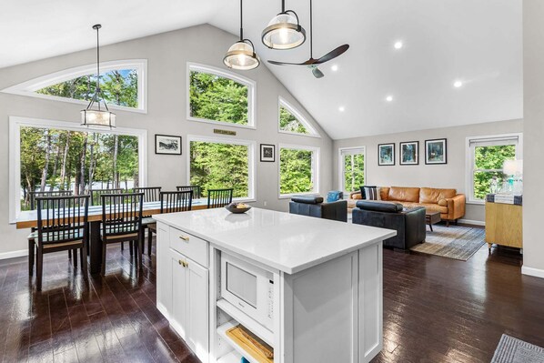 Une cuisine spacieuse avec un grand îlot central, un coin repas avec des chaises et un salon avec un canapé et une table basse.