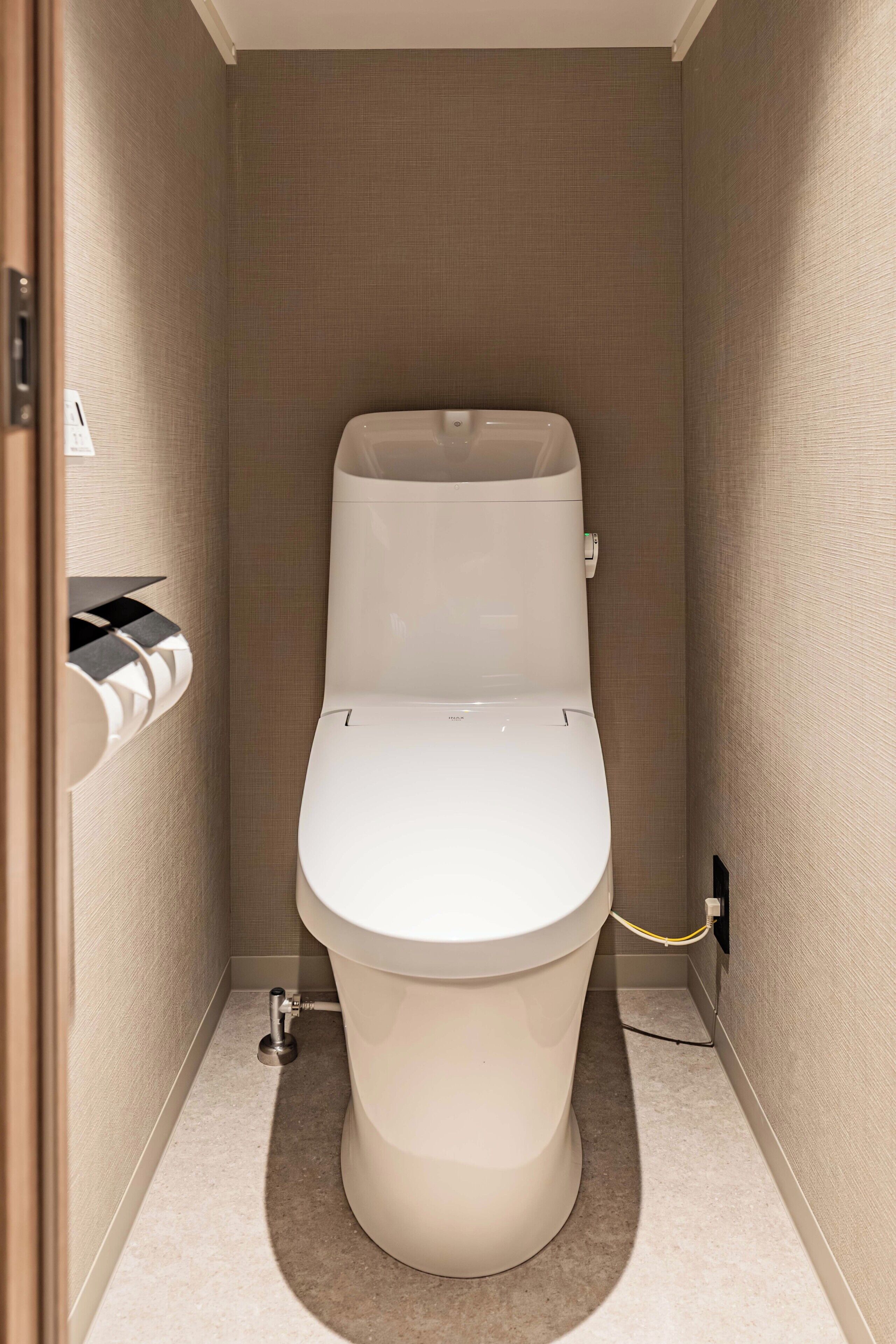 A small, modern bathroom with a toilet, a hand dryer, and a towel rack.