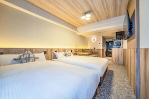 Ein Hotelzimmer mit zwei Betten, einem Fernseher, einem kleinen Tisch und einem durchgegangenen Badezimmereingang.