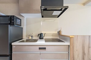 Eine Küche mit einem Edelstahl-Kühlschrank, einem Einbauofen, einer Mikrowelle und einem Spülbecken.