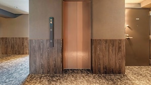 An elevator with a digital display, a door, and a textured wall. - Apartment Hotel 11 Namba 2 (Osaka-shi)