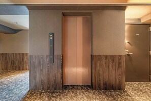 Ein Aufzug mit digitaler Anzeige, einer Tür und einer strukturierten Wand.