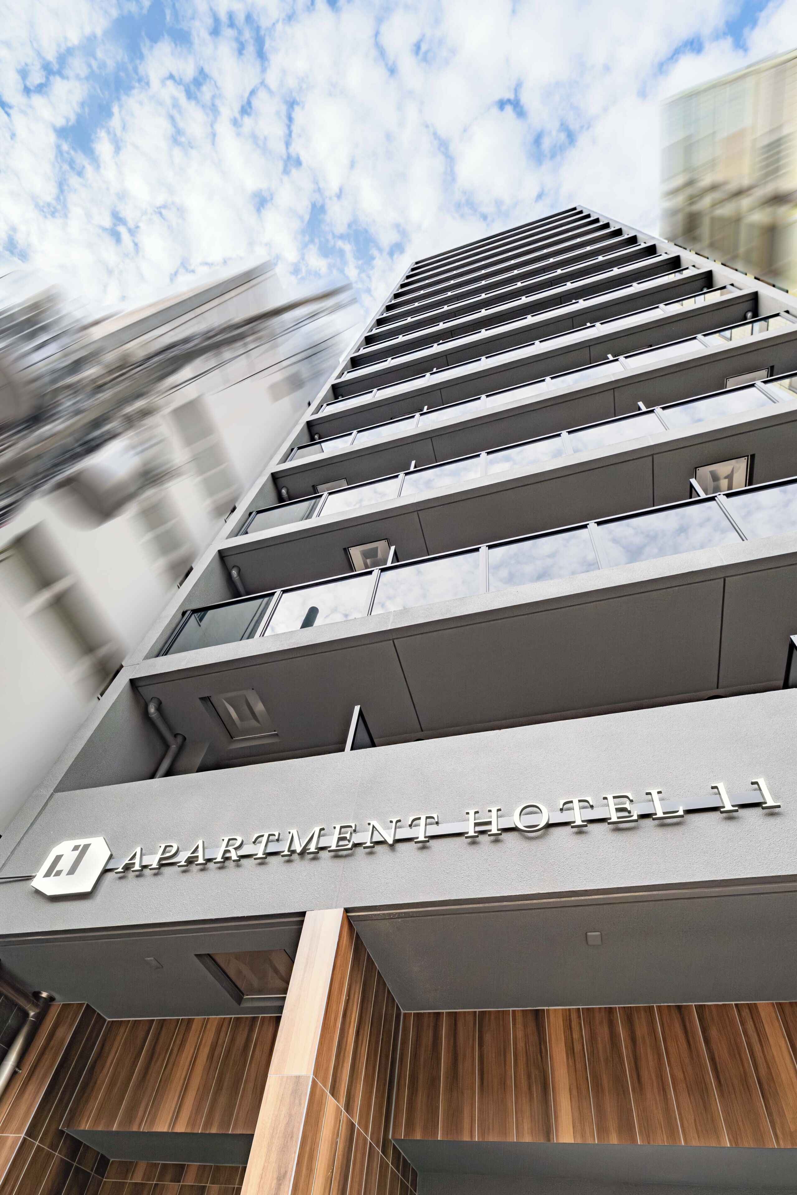 A modern building with a sign reading 'APARTMENT HOTEL 11'.