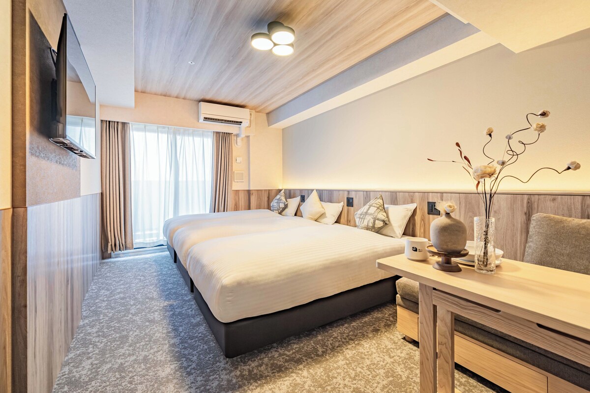Ein modernes Hotelzimmer mit einem großen Bett, einem Schreibtisch und einer Vase mit Zweigen.