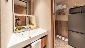 A modern bathroom with a white sink, mirror, and a small plant. - Apartment Hotel 11 Namba 2 (Osaka-shi)