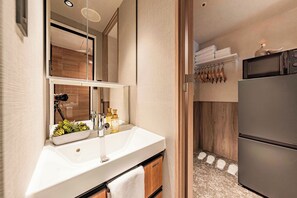 Ein modernes Badezimmer mit Waschbecken, Spiegel und einer kleinen Pflanze.