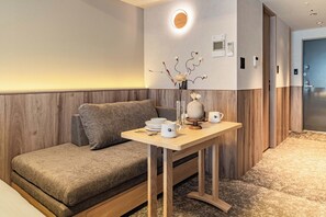 A modern hotel room with a sofa, a small table with a vase and cups, and a wall-mounted light fixture. - Apartment Hotel 11 Namba 2 (Osaka-shi)