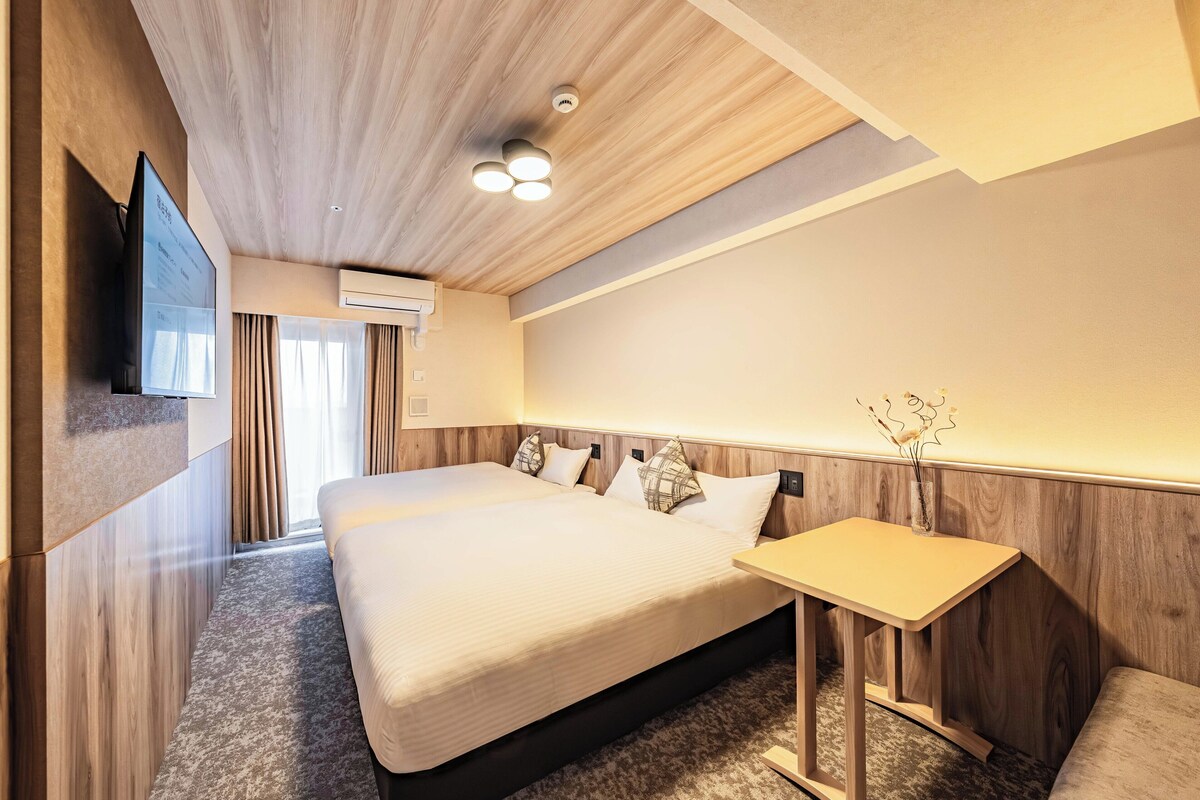 Ein modernes Hotelzimmer mit einem großen Bett, einem Nachttisch, einem Flachbildfernseher und einer Klimaanlage.