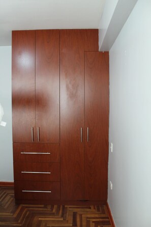 Une grande armoire en bois, dotée de deux portes et d’un tiroir.