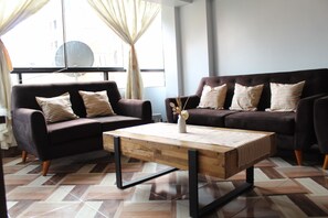 Ein modernes Wohnzimmer mit zwei Sofas, einem Couchtisch und einem großen Fenster mit Vorhängen.