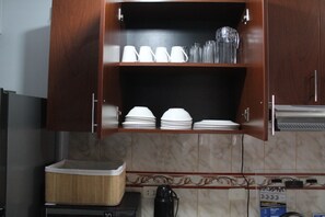 Eine Küche mit einem Holzschrank, der weiße Tassen, Gläser und Teller beherbergt.