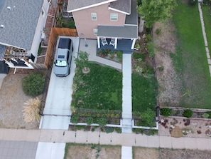 A residential area with a paved driveway, a parked car, and a lawn. - 3-bedroom, 2-bath single-family home with yard and parking (Denver)