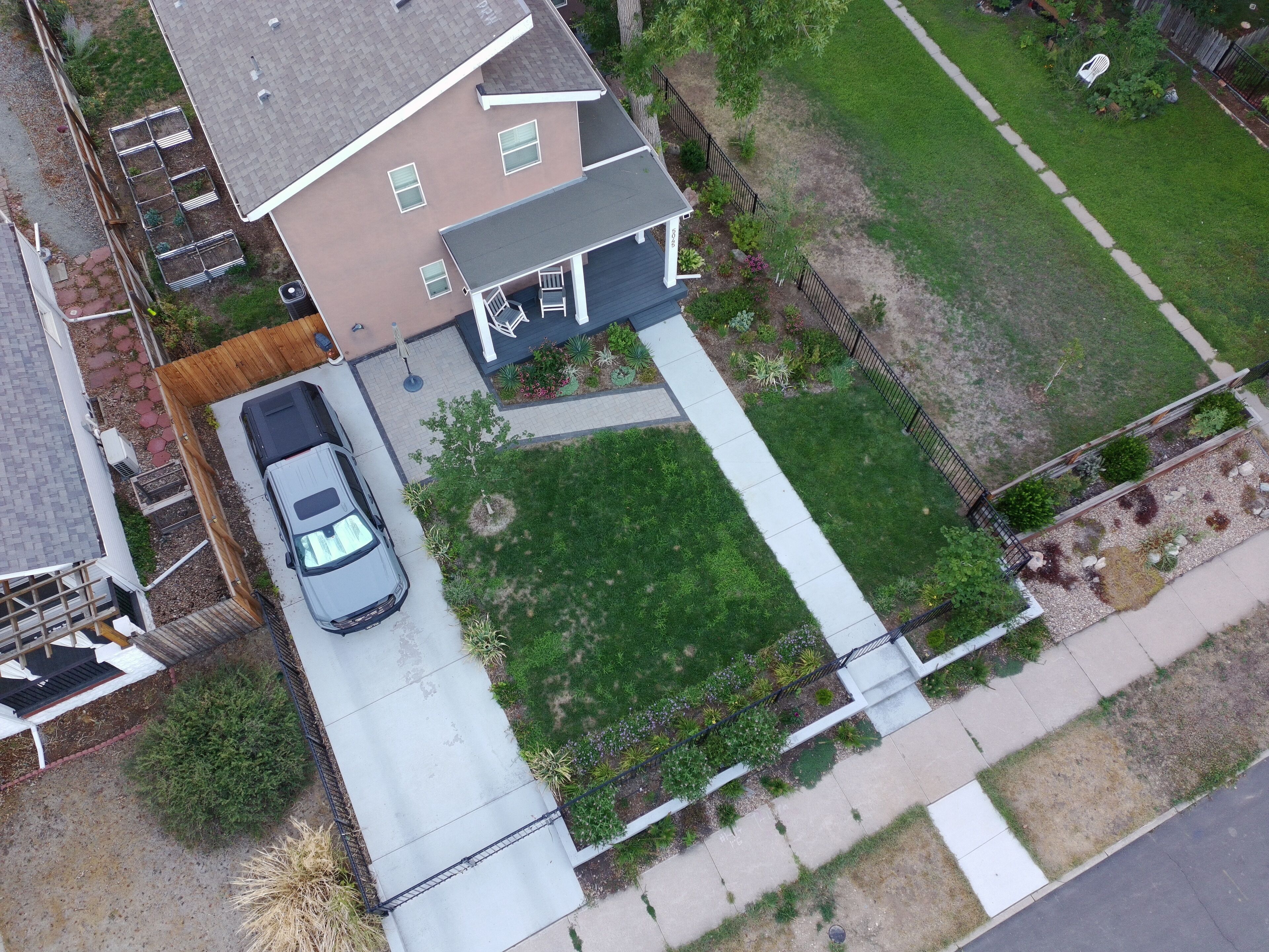 An aerial view of a residential property with a two-car garage, a lawn, and a pathway leading to the house.