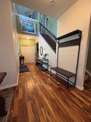 A spacious room with a wooden floor, a staircase, and a wall-mounted rack. - 3-bedroom, 2-bath single-family home with yard and parking (Denver)