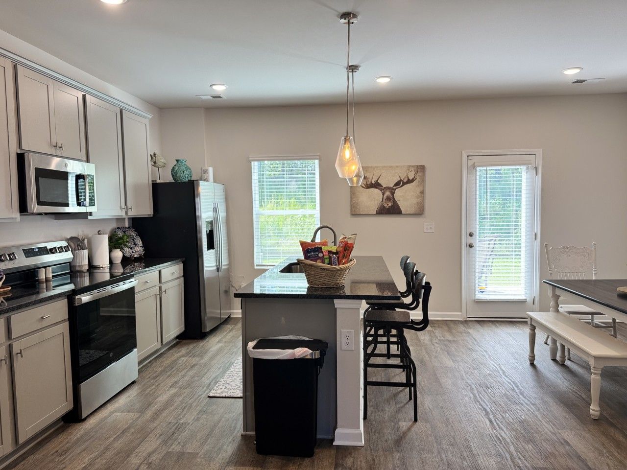 A modern kitchen with a central island, stainless steel appliances, and a dining area with a bench.