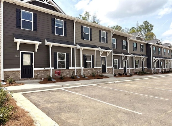 A row of townhouses with a parking lot in front.