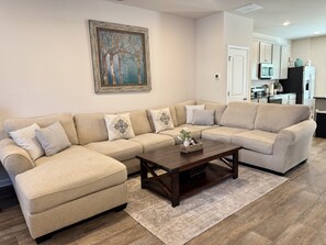 A living room with a sectional sofa, a coffee table, and a painting on the wall.
