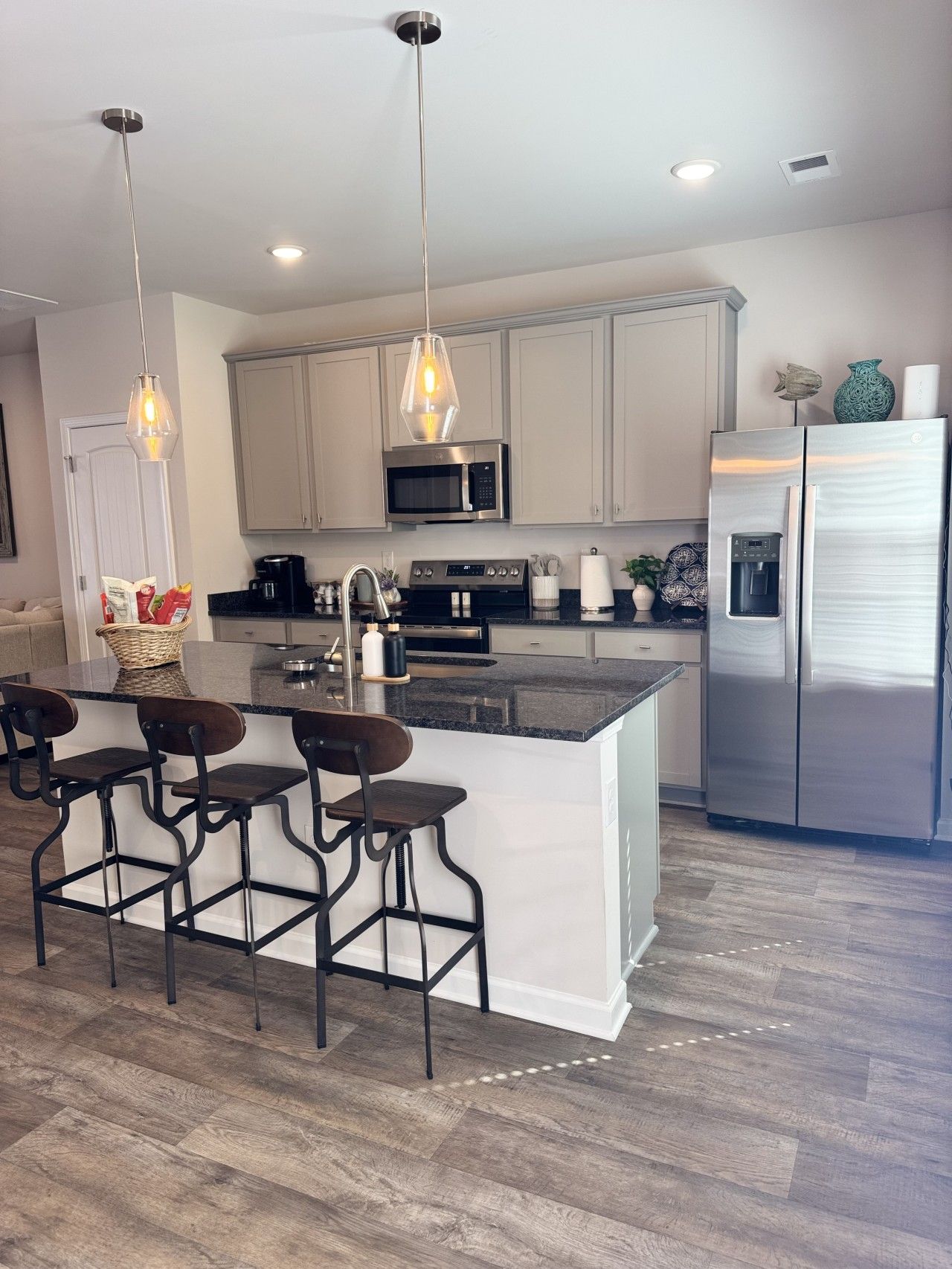 A modern kitchen with a central island, stainless steel appliances, and pendant lighting.