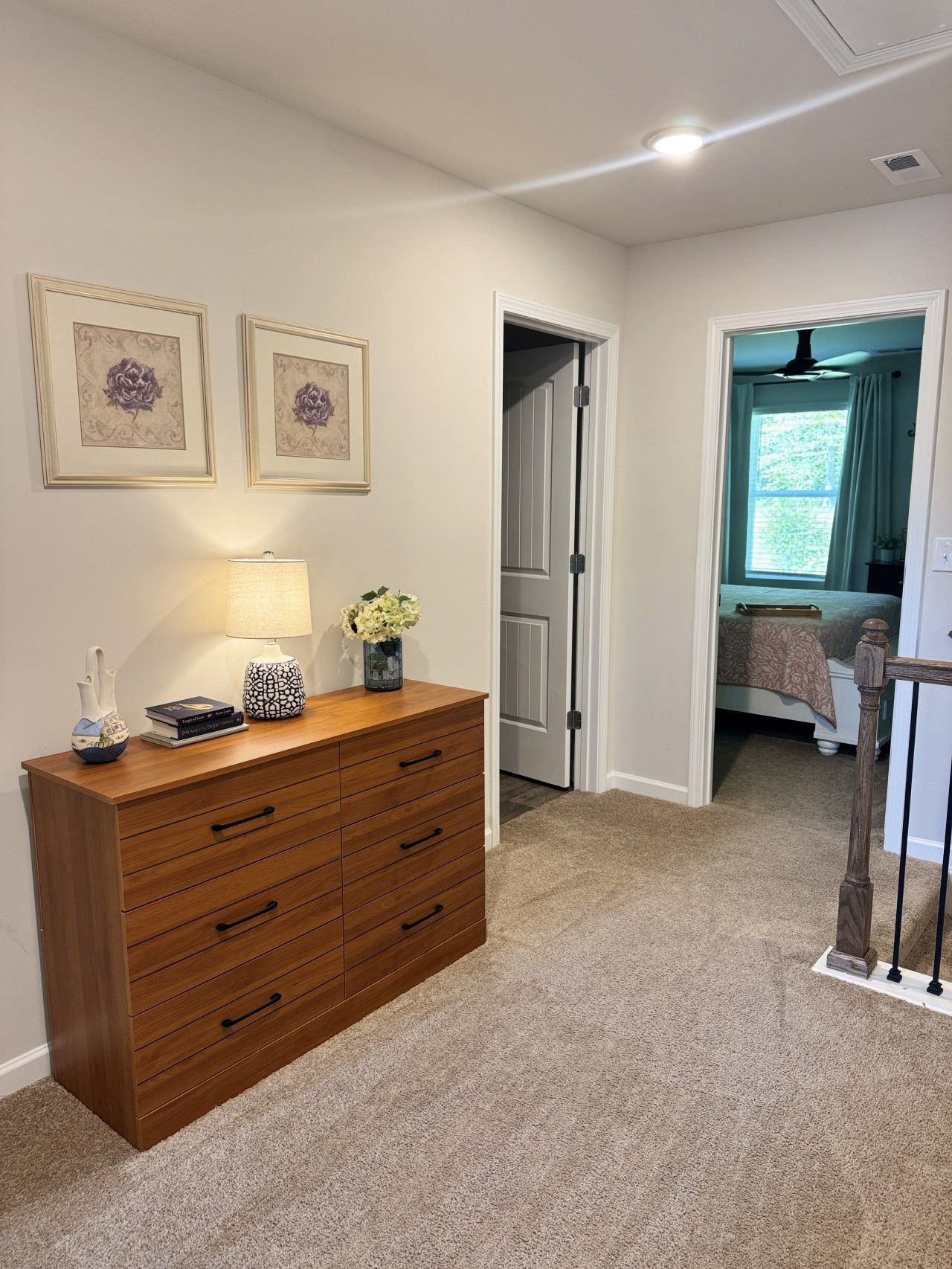 A bedroom with a bed, a nightstand, a dresser, and a window with curtains.
