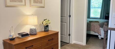 A bedroom with a bed, a nightstand, a dresser, and a window with curtains.