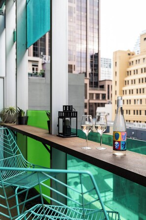 A balcony with two glasses of white wine, a bottle, and a black lantern on a wooden ledge. - Spacious Vibey Retreat with a Movie Projector, Electric Recliner and & Balcony (Melbourne)