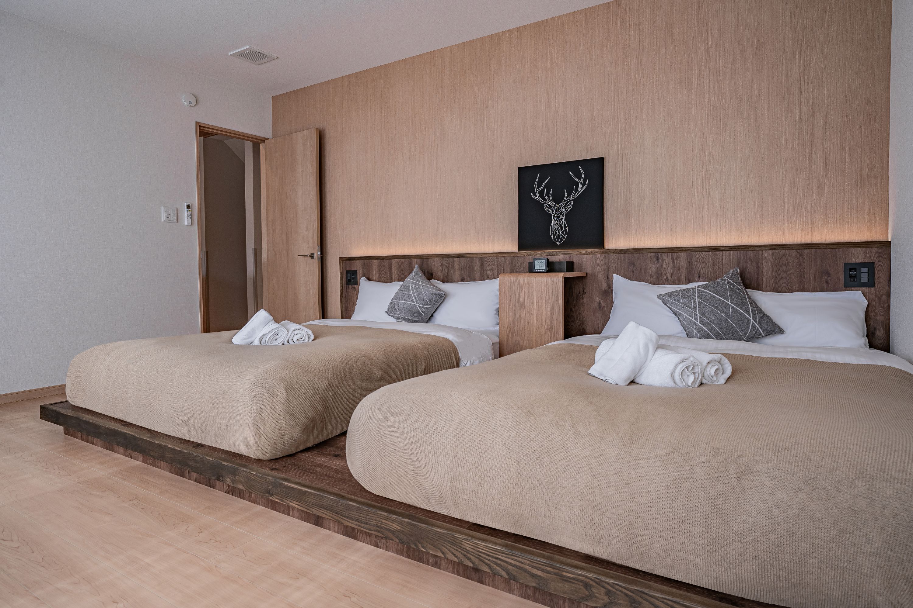 Habitación de hotel con dos camas, cabeceros de madera y una obra de arte colgada en la pared.