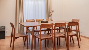Un coin repas avec une table et des chaises en bois, un vase contenant des fleurs séchées et une boîte de mouchoirs.